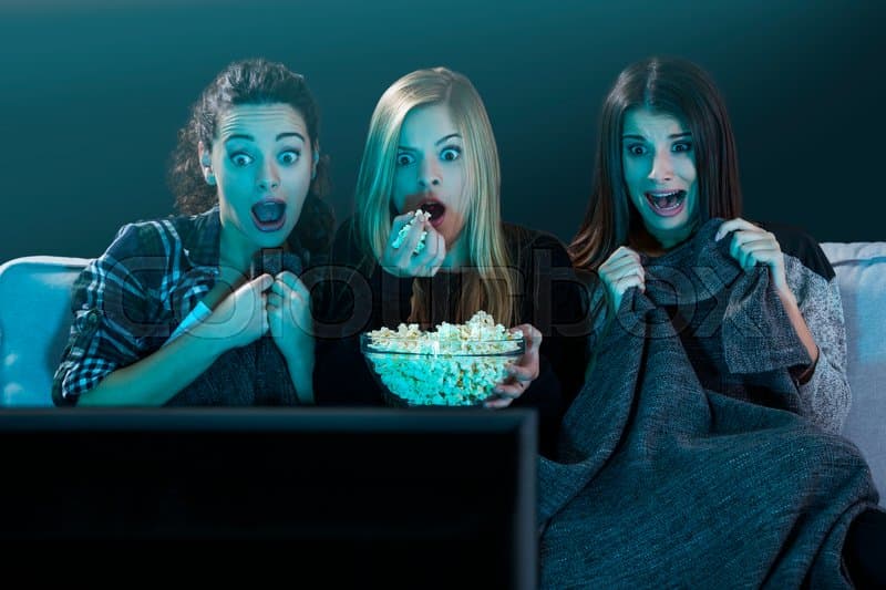 سه دختر نوجوان درحال خوردن پاپ‌کرن فیلم ترسناک نگاه می‌کنند