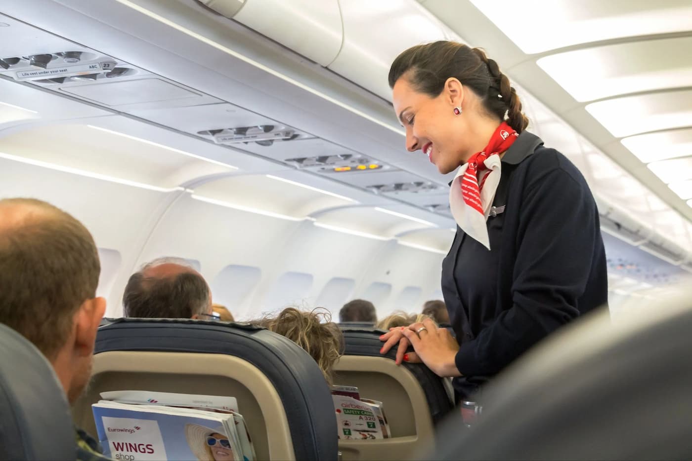 مهماندار خانمی که با لبخند در حال صحبت با مسافرین هواپیماست