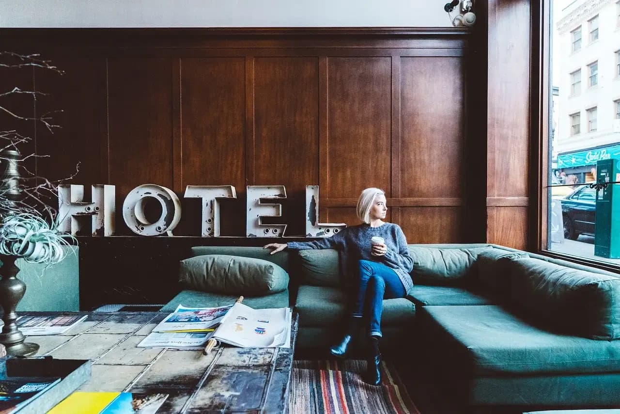 تصویری از لابی یک هتل که زنی در آن نشسته است.