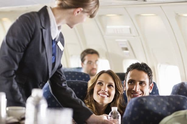 تصویری از مهماندار هواپیما که در حال صحبت با دو مسافر است